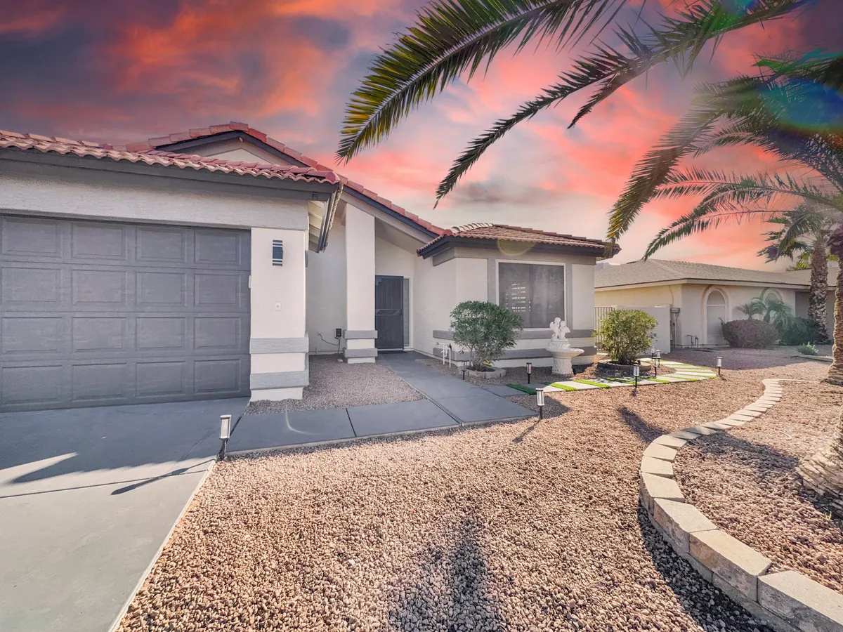 Featuring a welcoming front entrance flanked by palm trees and detailed landscaping, this scene captures the inviting exterior of the property. The driveway and porch hint at a space ready for socializing and outdoor activities.
