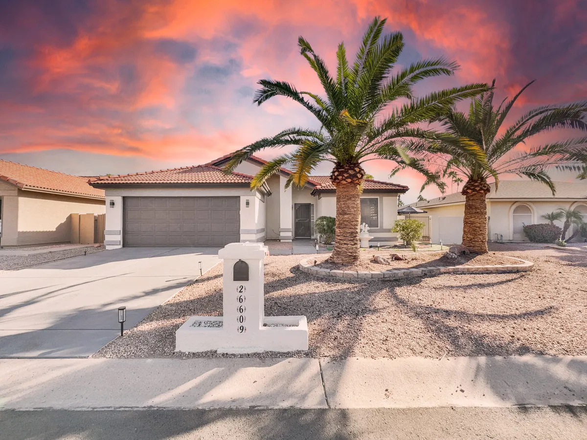 The exterior of a home framed by tall palm trees, featuring a welcoming front entrance and a hint of landscaping. The scene suggests a community designed for relaxation and neighborly interaction.